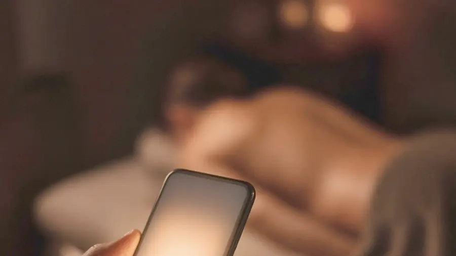 Erotic massage near me - phone glowing in a dim room, booking a session by message